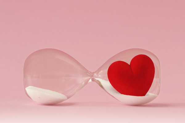 Clessidra con un cuore rosso al suo interno, simbolo del rapporto tra tempo, cura e attenzione nel lavoro.